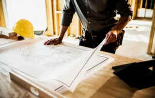 Building Contractor Looking Over Blueprints At Home Construction Site.