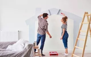 Young,Couple,Painting,The,Interior,Wall,In,Their,New,Apartment